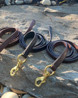Ravenox leather horse leads in Chestnut, Dark Brown, and Black, artistically arranged on rugged rocks. (8213561540845)