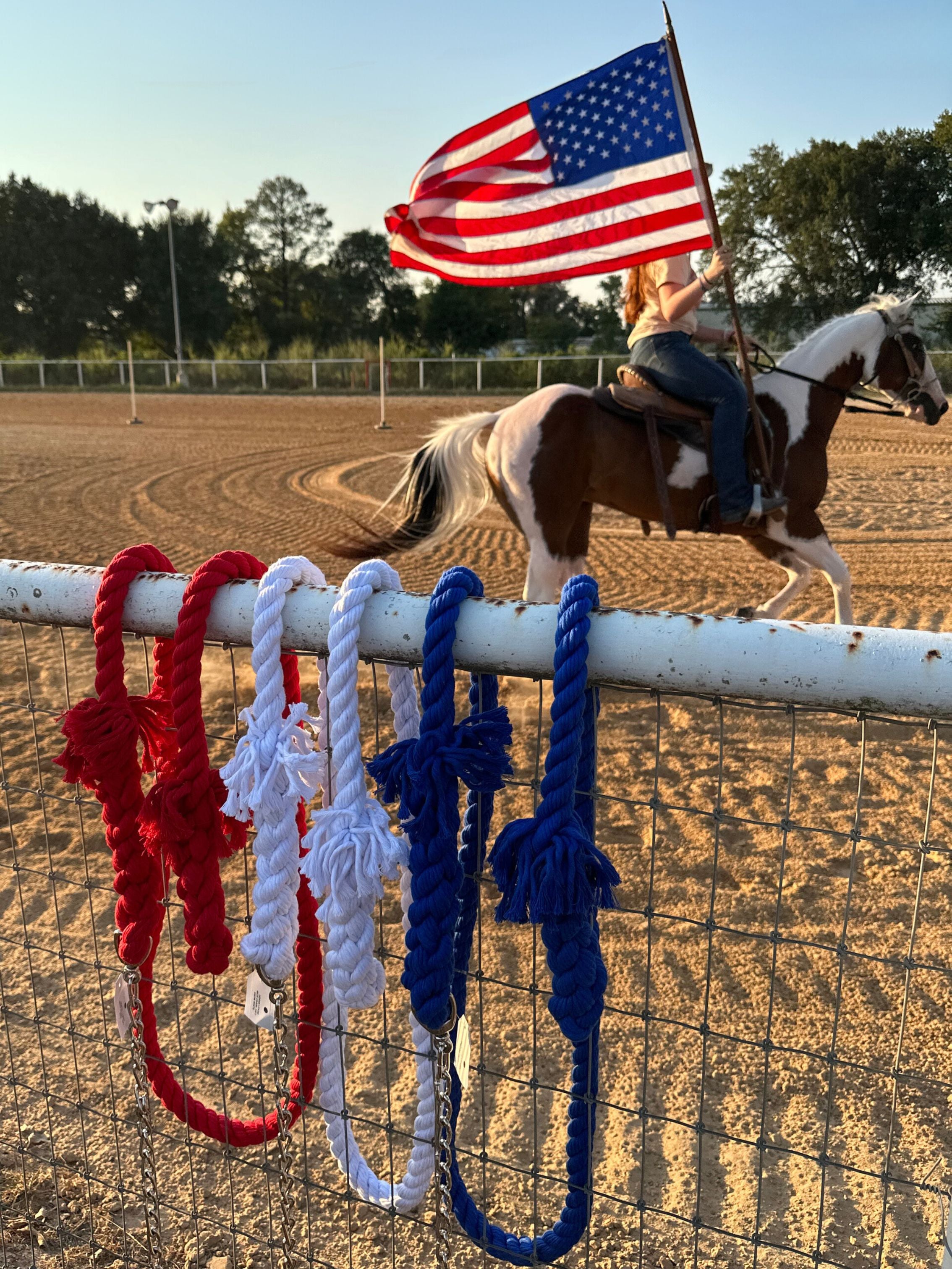 Ravenox red, white, and blue twisted cotton horse leads with chain and snap, displayed at a horse rodeo with an American flag in the background. (1806013268058)