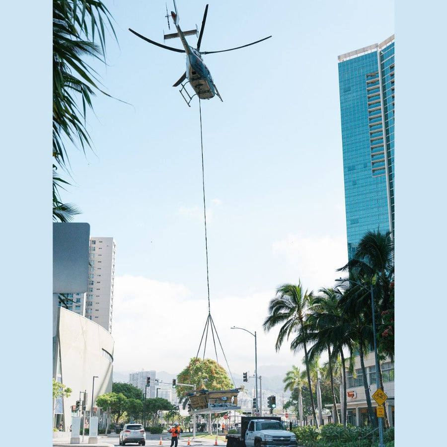 A helicopter, using Ravenox Synthetic Helicopter Longlines, hoists a jacuzzi onto the rooftop of a high-rise condominium in Hawaii. The longlines, made from ultra-strong and lightweight HMPE fiber, demonstrate their low-stretch and high-strength capabilities in this demanding lifting operation. The scene captures the practical use of these longlines, highlighting their durability and safety features essential for heavy-lift helicopter operations. (7552156795117)