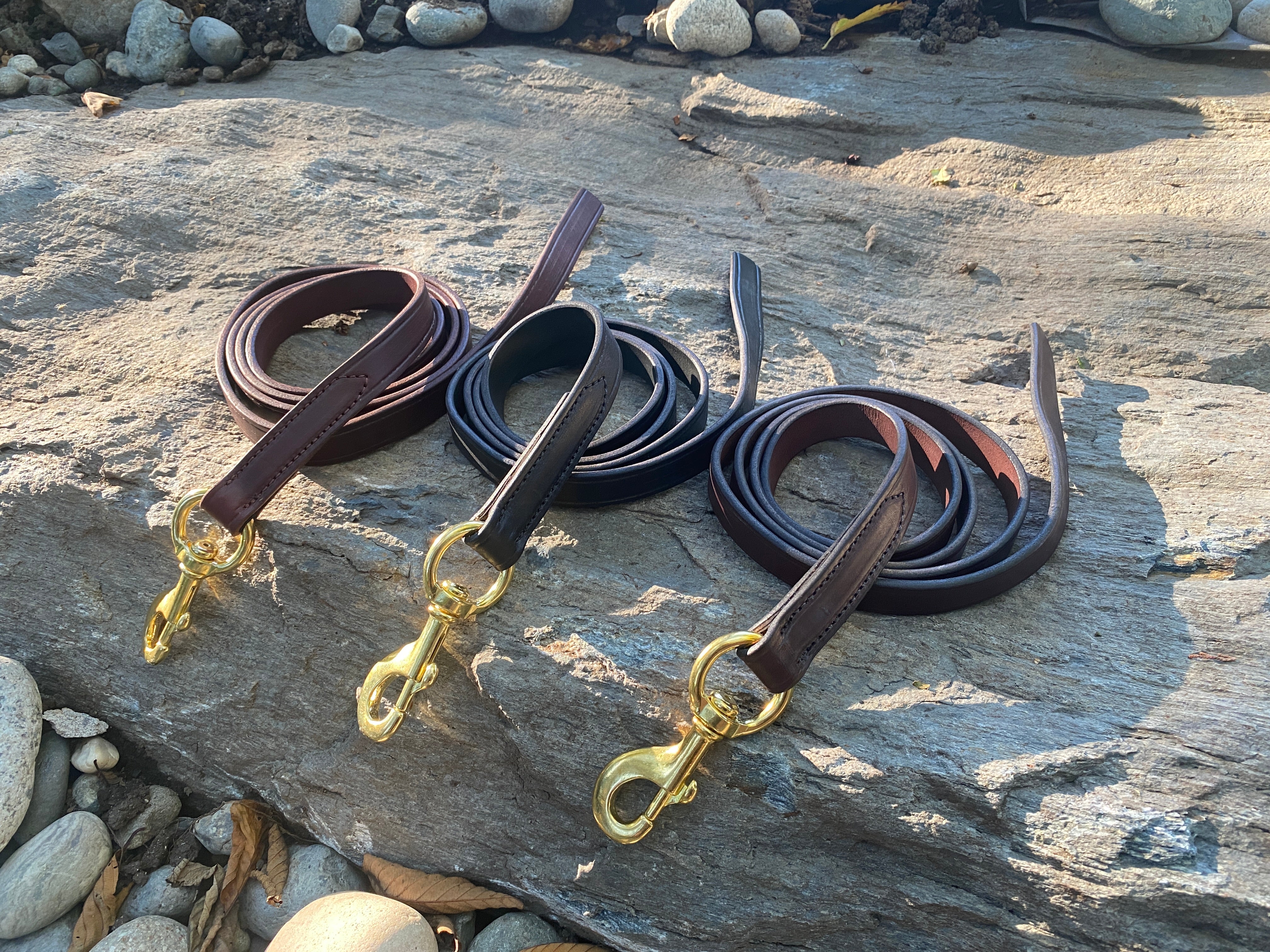 Ravenox leather horse leads in Chestnut, Dark Brown, and Black, artistically arranged on rugged rocks. (8213561540845)