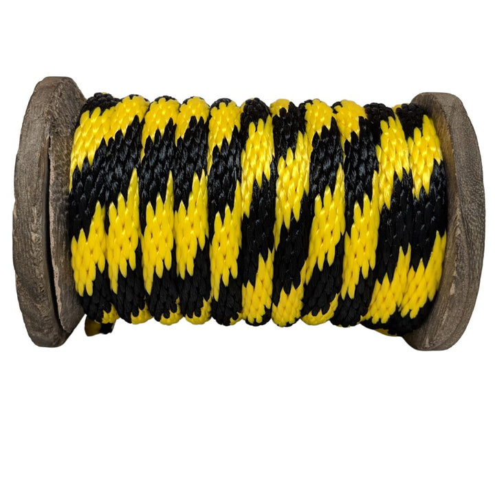 Close-up of a Ravenox black and gold/yellow solid braid polypropylene derby rope neatly coiled on a wooden spool. (8217688637677)