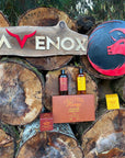 A rustic wood pile featuring a collection of Leather Honey leather care products alongside the Ravenox logo. (8289571373293)
